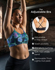 A woman in a gym wearing a patterned sports bra with her arms raised, alongside a circular inset showing the back of the adjustable bra and text listing features like 5-way straps, stash pockets, ruching, a non-chafe band, and removable lights-out pads.
